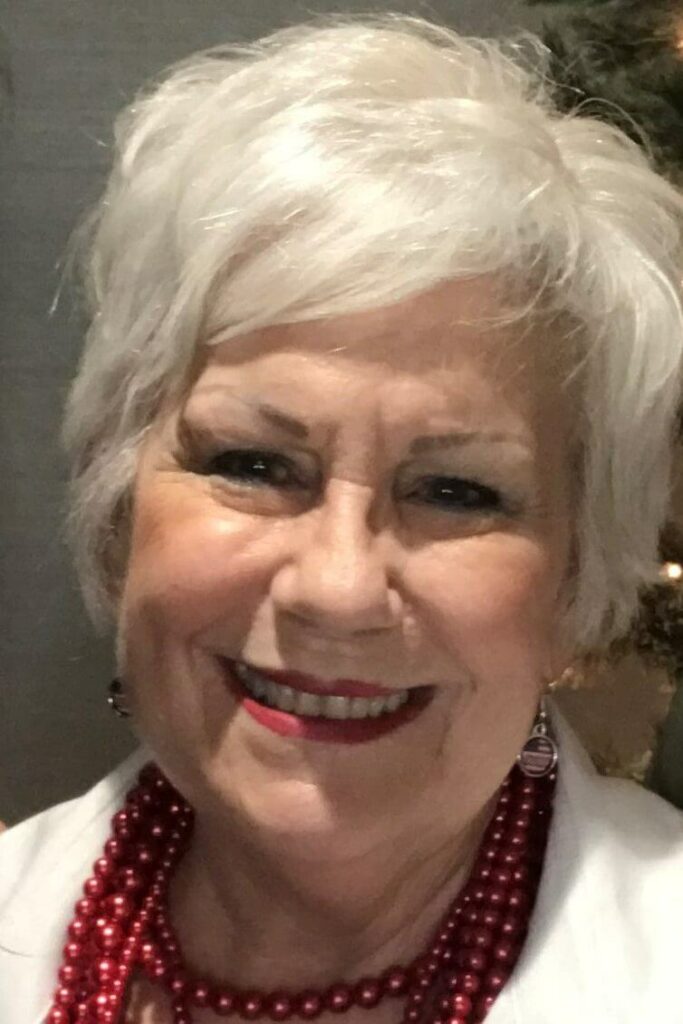 A woman with white hair and red earrings.