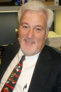 A man with white hair and wearing a suit.