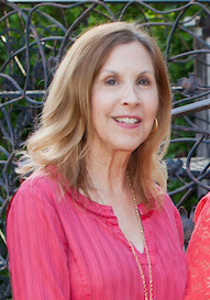 A woman in pink shirt smiling for the camera.