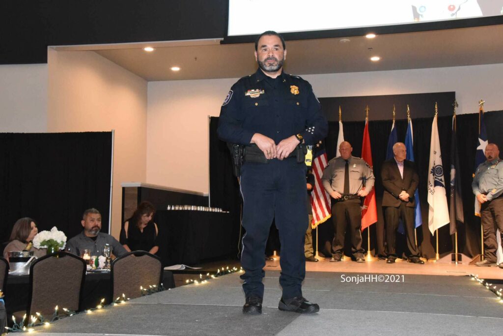 A police officer standing on stage in front of people.