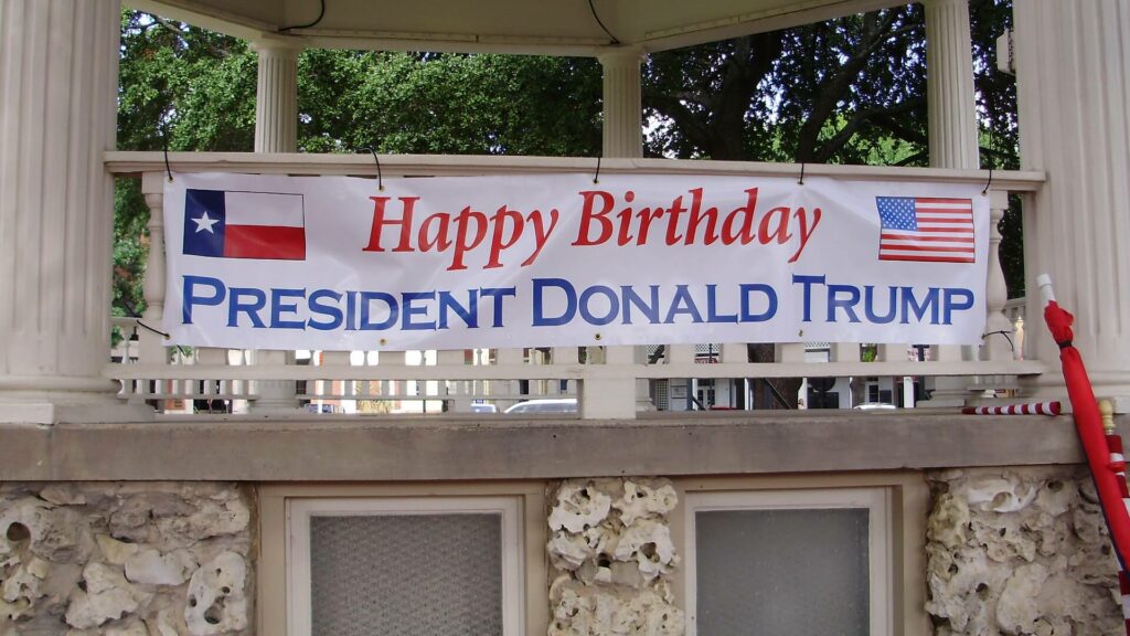 A happy birthday banner hanging from the side of a building.