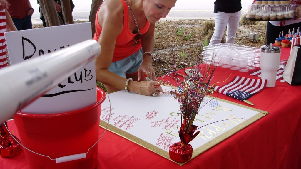 A woman writing on a paper at an event.