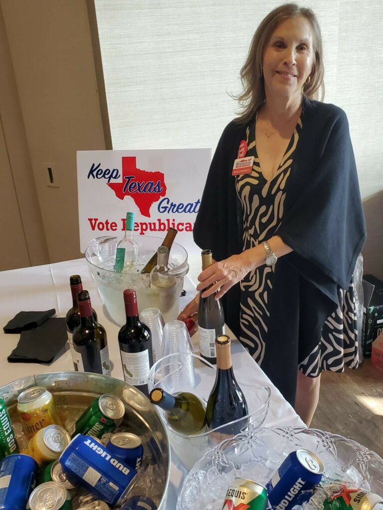 A woman standing next to a table with wine and other bottles.