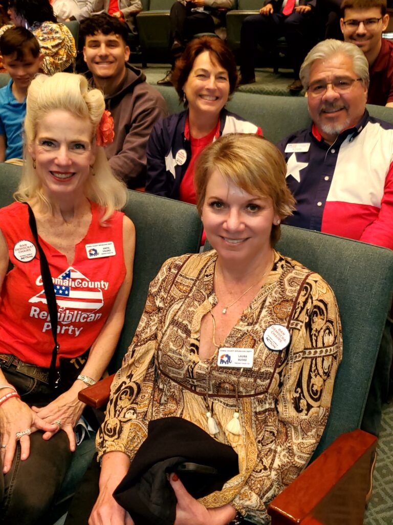 A group of people sitting in chairs with badges on their shirts.