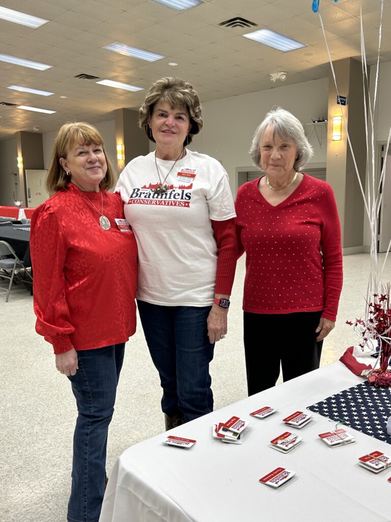 Three women standing in front of a table with red and white decorations.